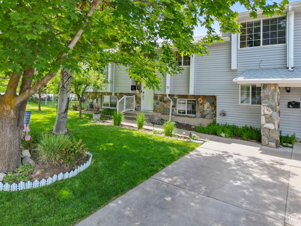 View of front of house featuring stone siding, a front lawn, and a shingled roof