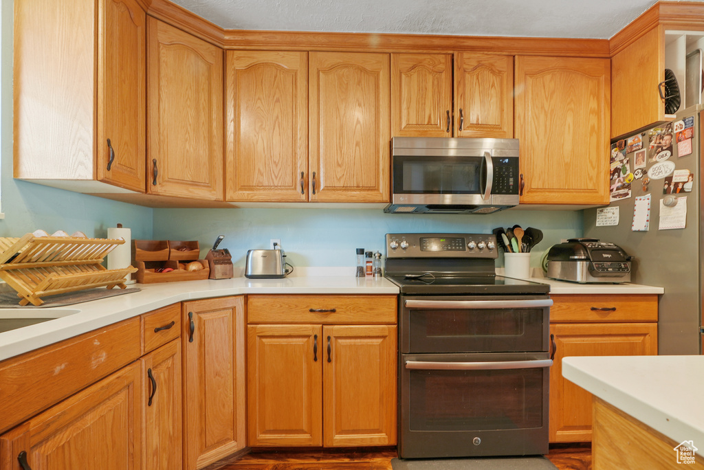 Kitchen featuring stainless steel appliances, light countertops, and wood finished floors