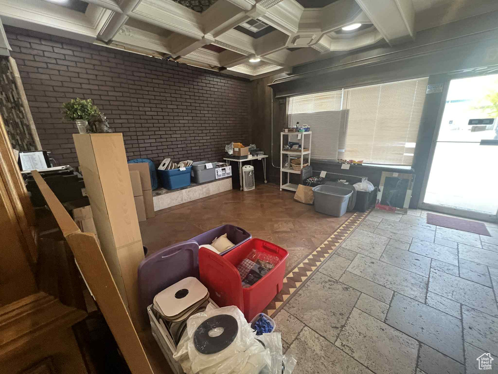 Misc room with plenty of natural light, beam ceiling, coffered ceiling, and stone tile flooring