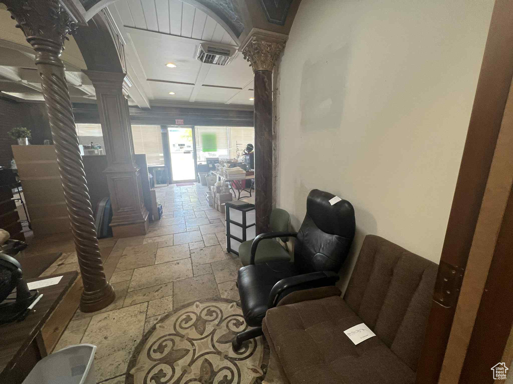 Hall with decorative columns, stone tile flooring, and recessed lighting