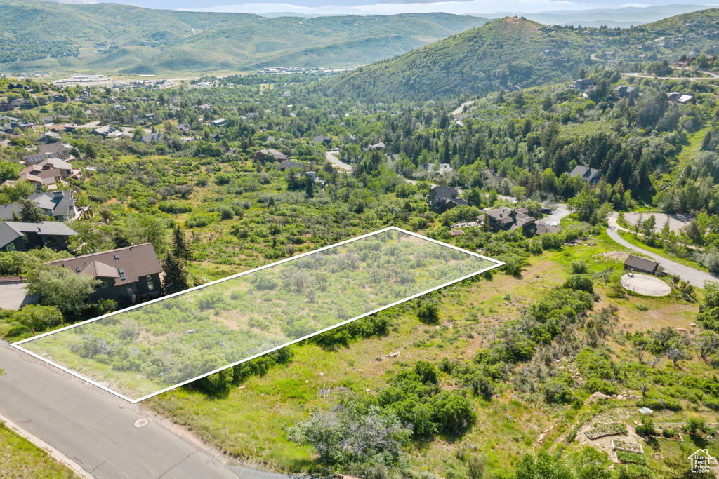 Aerial view of property and surrounding area featuring a mountainous background and property boundaries highlighted