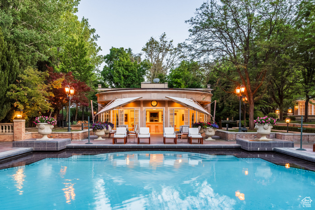 Outdoor pool with a storage structure, an outdoor structure, a patio area, and view of wooded area
