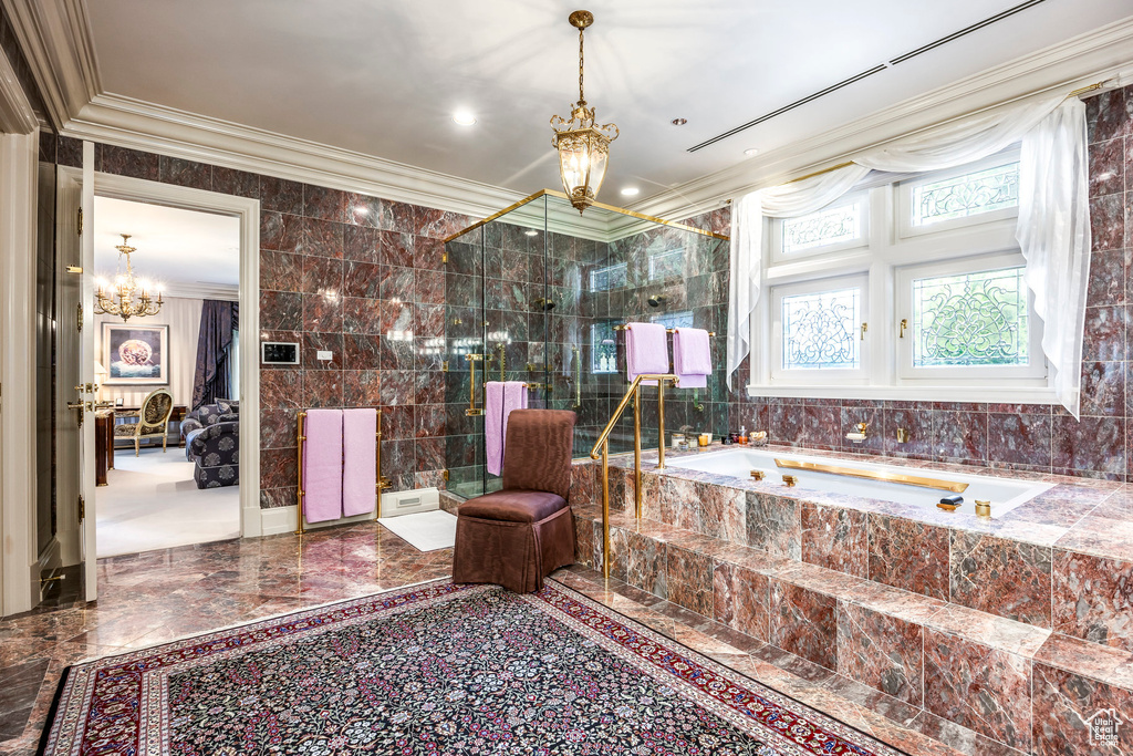 Bathroom featuring a chandelier, ornamental molding, a garden tub, tile walls, and marble tiled floors