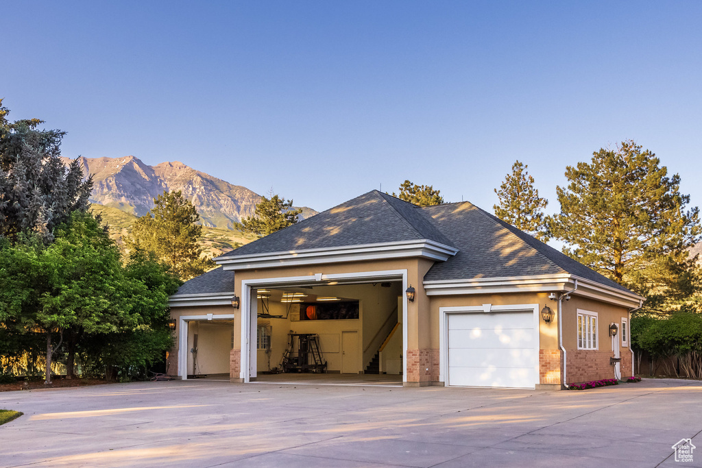 View of side of property featuring driveway, a garage, a mountain view, brick siding, and stucco siding