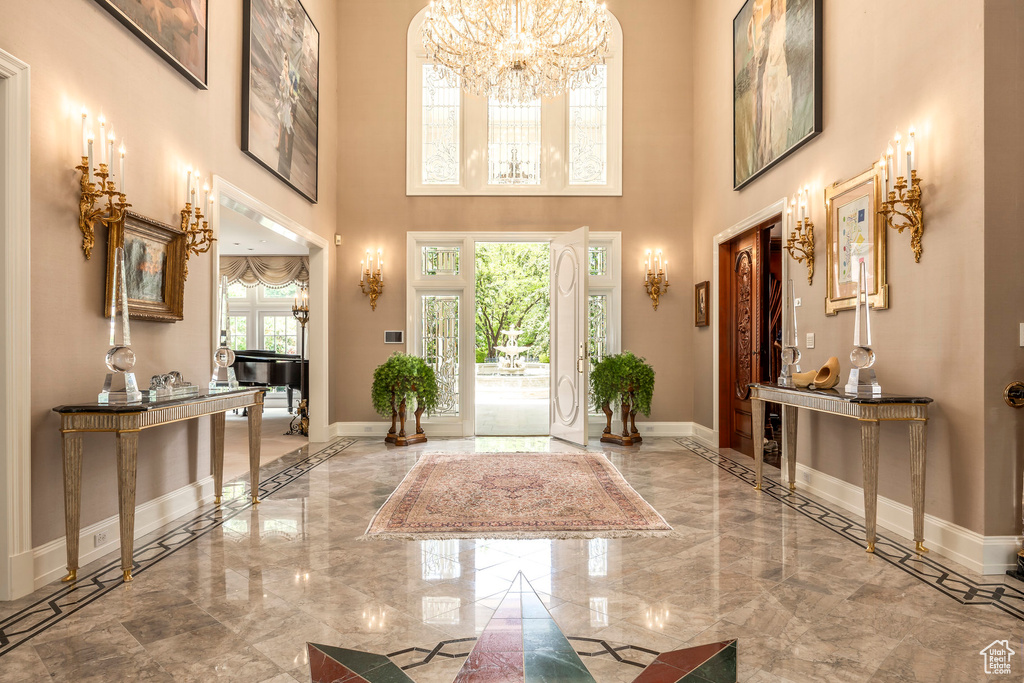Entryway featuring marble tiled flooring, a high ceiling, and a chandelier