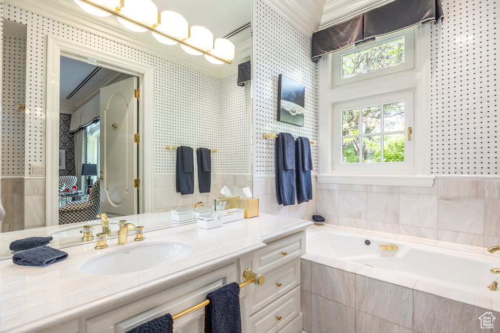 Bathroom with crown molding, a garden tub, and vanity