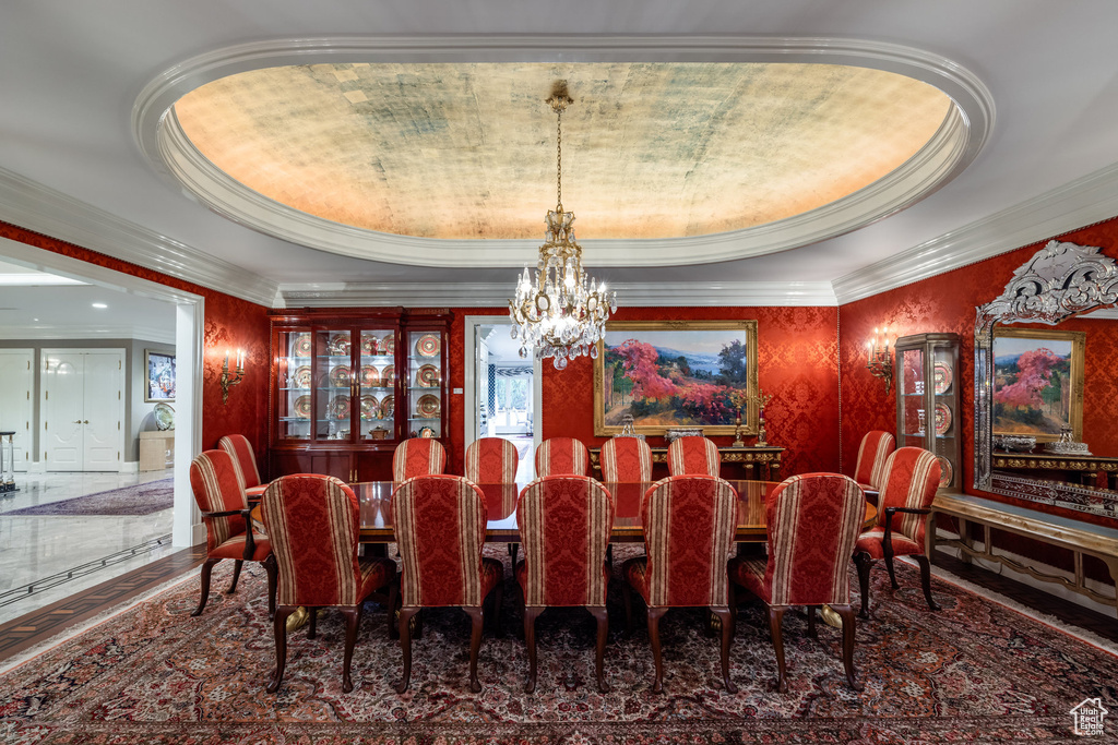 Dining space featuring a tray ceiling, crown molding, and a chandelier