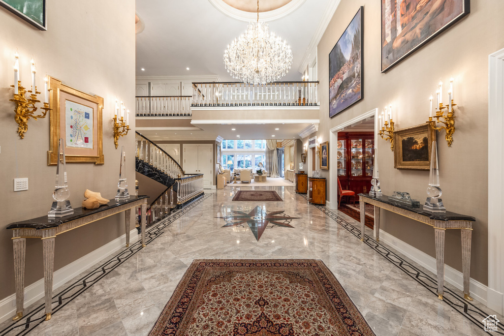 Foyer entrance featuring stairs, a high ceiling, ornamental molding, marble tiled floors, and a chandelier