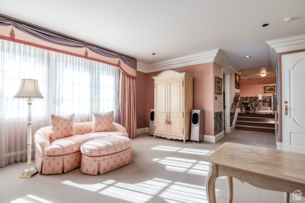 Living area featuring light colored carpet, ornamental molding, and stairway