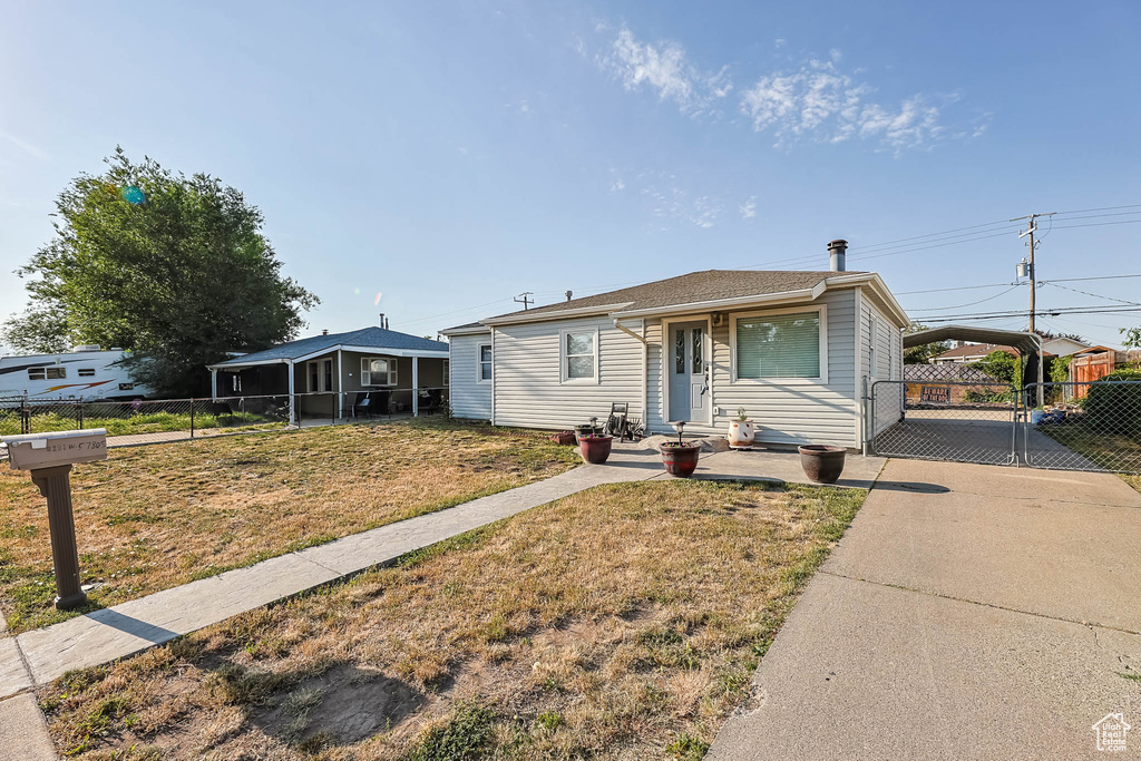 View of front of house with a sunroom, driveway, and a gate