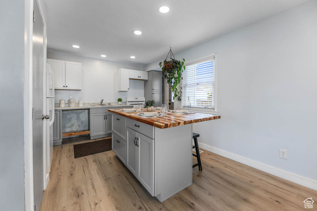 Kitchen featuring butcher block countertops, light wood-style flooring, a kitchen breakfast bar, recessed lighting, and a center island