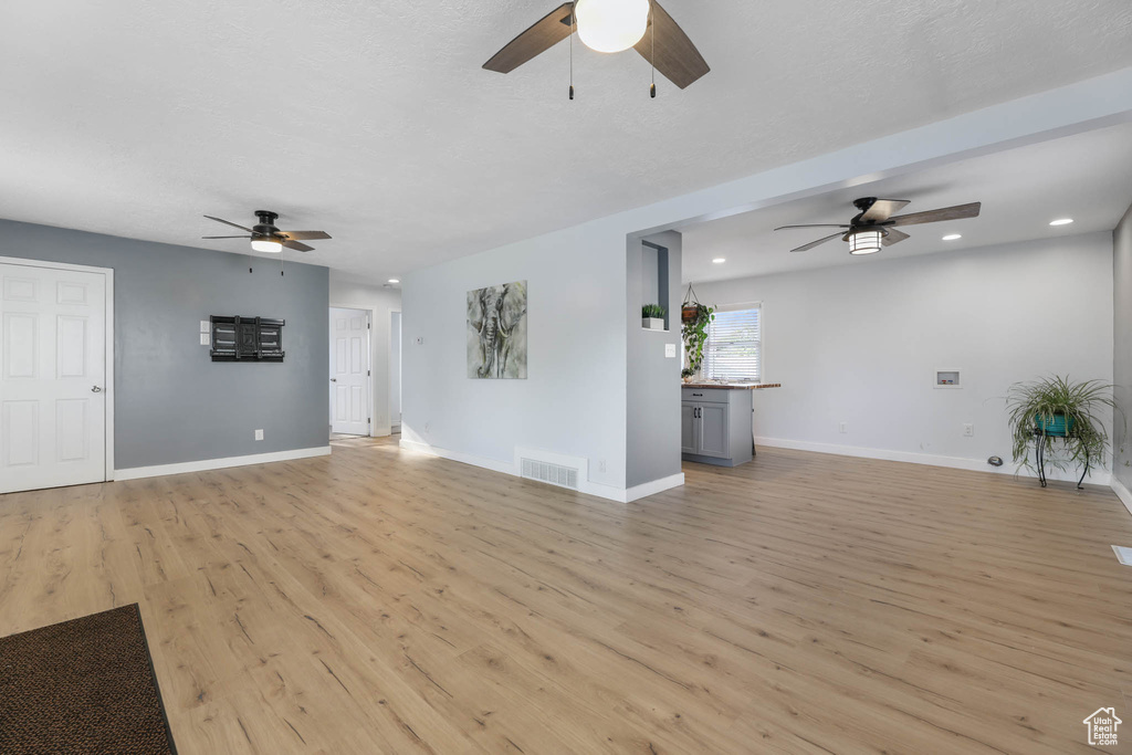 Unfurnished living room featuring a ceiling fan, light wood-style floors, and recessed lighting