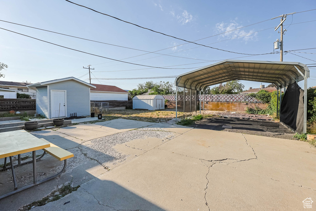 View of patio / terrace featuring a shed, a detached carport, and concrete driveway