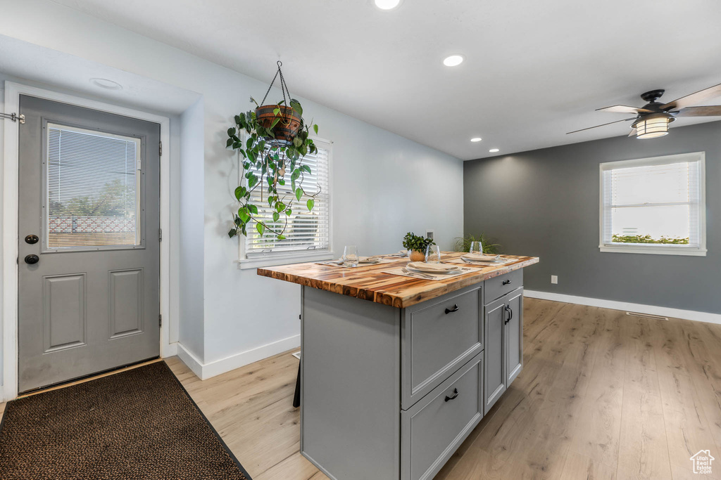 Kitchen with wooden counters, gray cabinetry, a center island, light wood-style floors, and healthy amount of natural light