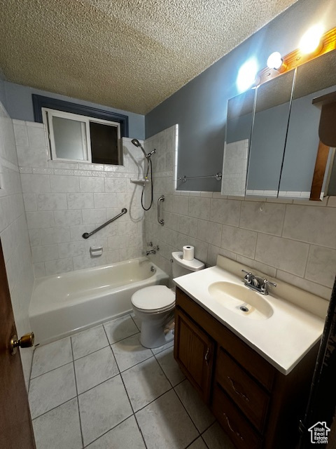 Full bathroom featuring a textured ceiling, bathing tub / shower combination, tile patterned floors, tile walls, and vanity