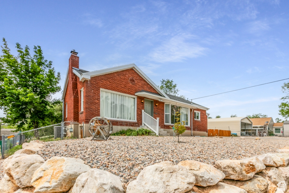 View of front of home with brick siding and a chimney