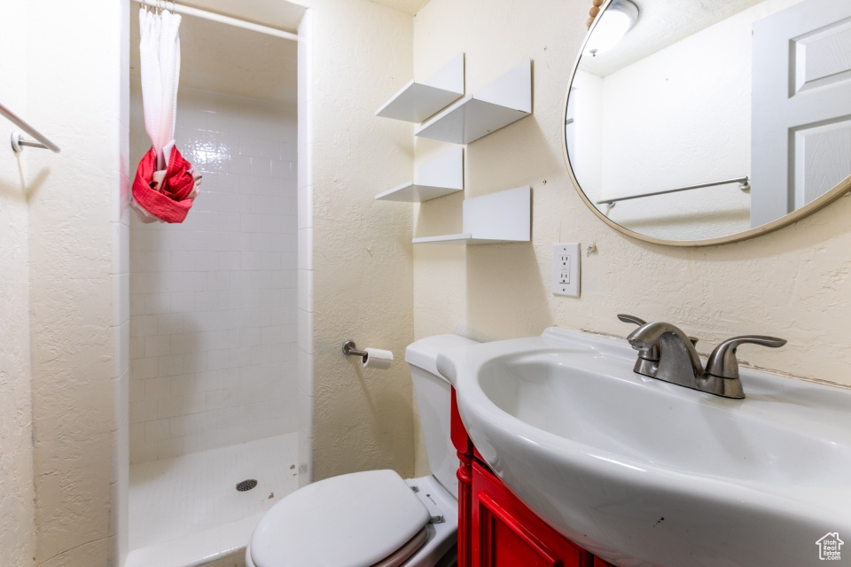 Full bathroom featuring a stall shower, a textured wall, and vanity