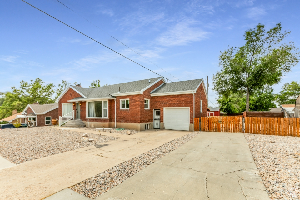 View of front of house featuring brick siding, a garage, concrete driveway, roof with shingles, and a chimney