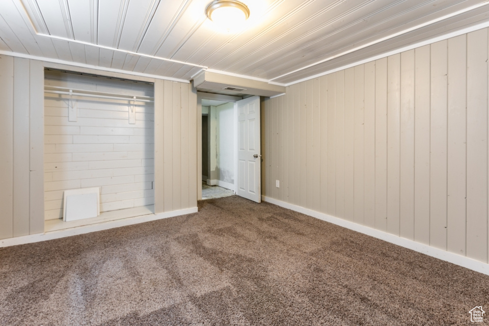 Unfurnished bedroom with carpet flooring and wooden walls