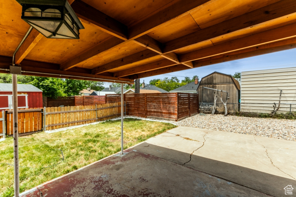 Fenced backyard featuring a storage shed and a patio