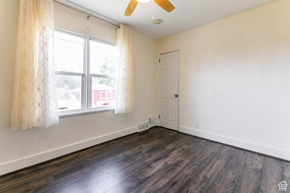 Empty room featuring dark wood-style floors, a ceiling fan, and a smoke detector