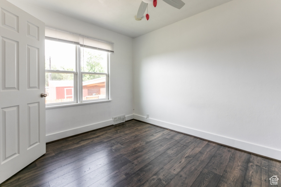 Empty room with dark wood-style flooring and ceiling fan