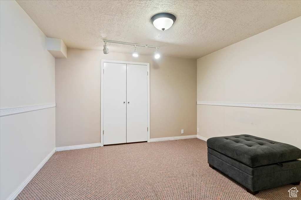 Unfurnished room with carpet floors, rail lighting, and a textured ceiling