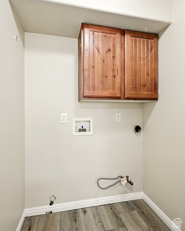 Laundry area with gas dryer hookup, washer hookup, cabinet space, and wood finished floors