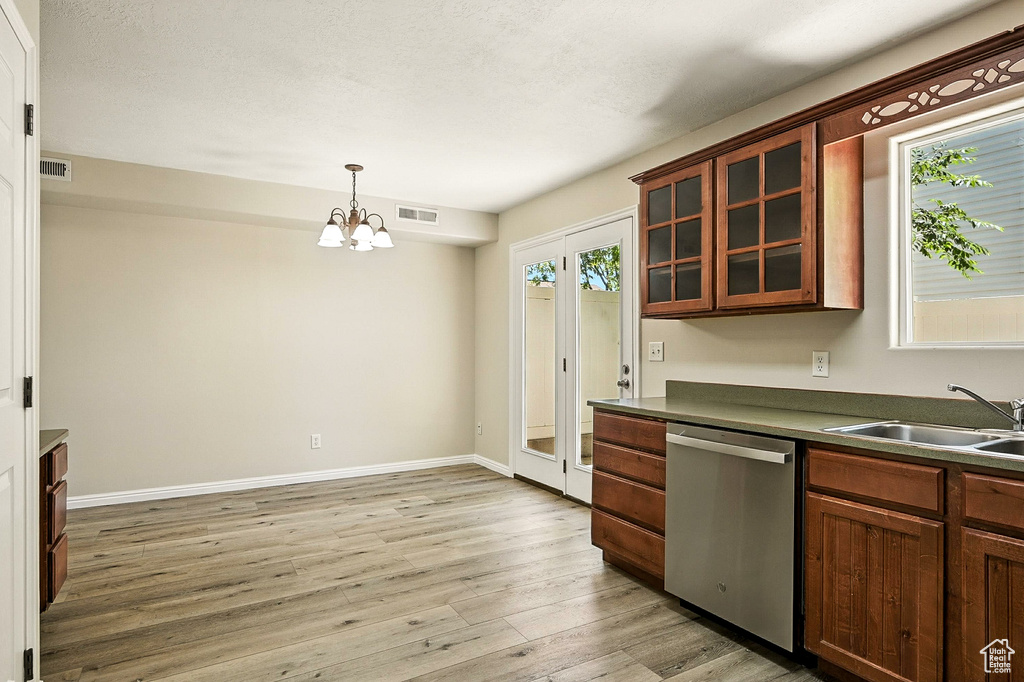Kitchen with dishwasher, light wood finished floors, dark countertops, a chandelier, and glass insert cabinets