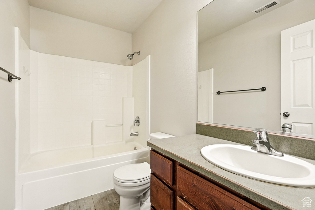 Bathroom with vanity, washtub / shower combination, and wood finished floors