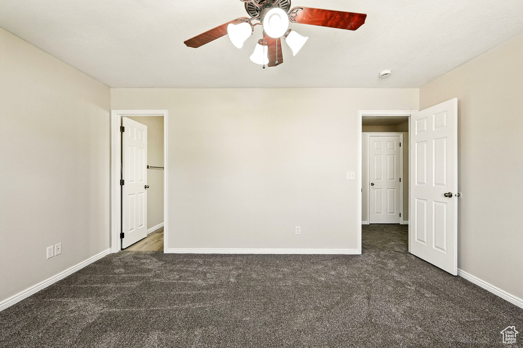 Unfurnished room with dark carpet and ceiling fan