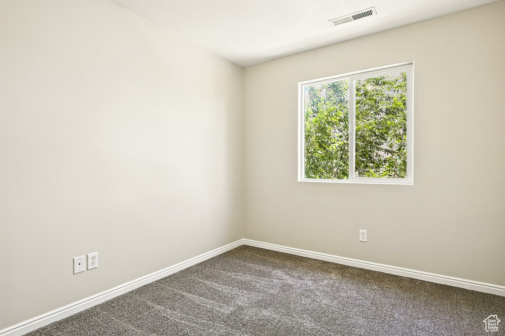 Empty room featuring baseboards and dark colored carpet