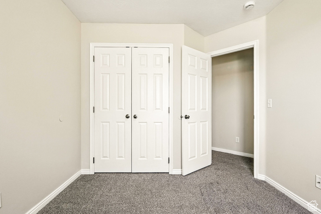 Unfurnished bedroom featuring dark carpet and a closet