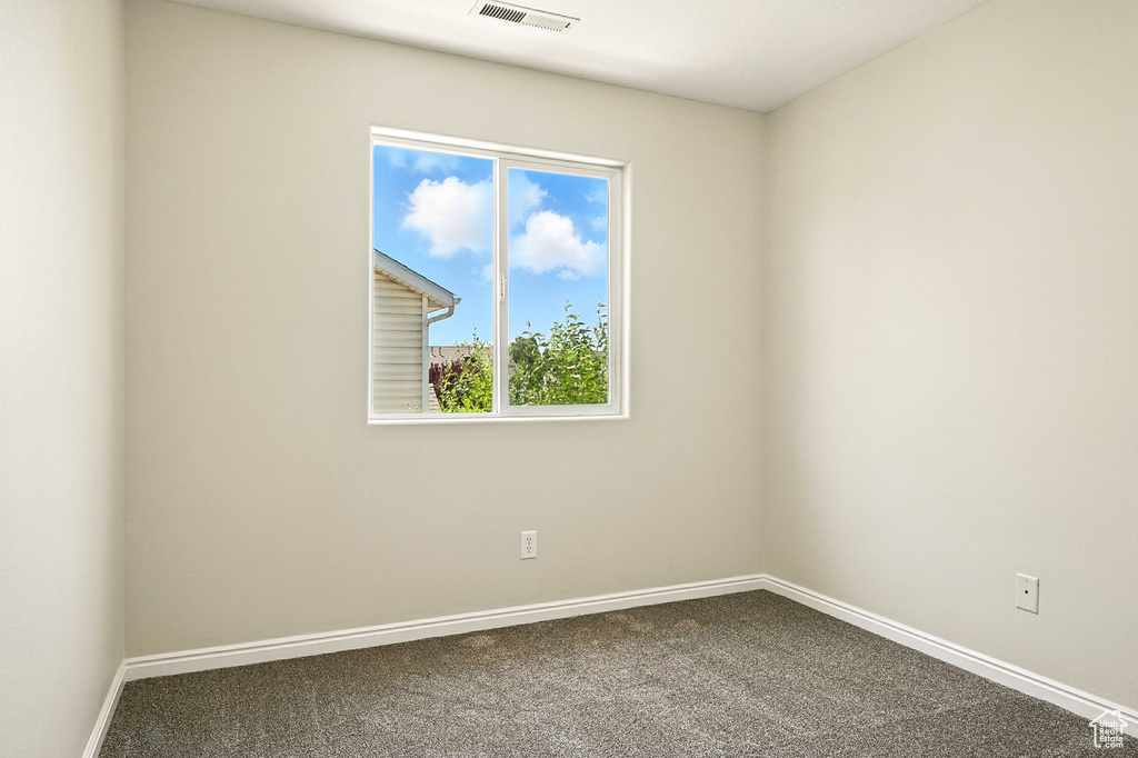 Unfurnished room featuring dark carpet and baseboards