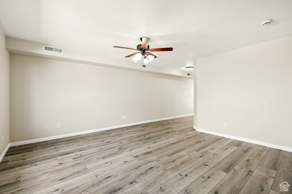 Unfurnished room featuring a smoke detector, a ceiling fan, and wood finished floors