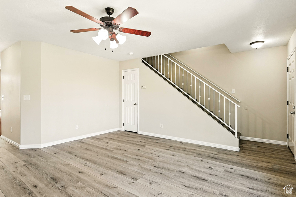 Unfurnished living room with wood finished floors, stairs, and a ceiling fan