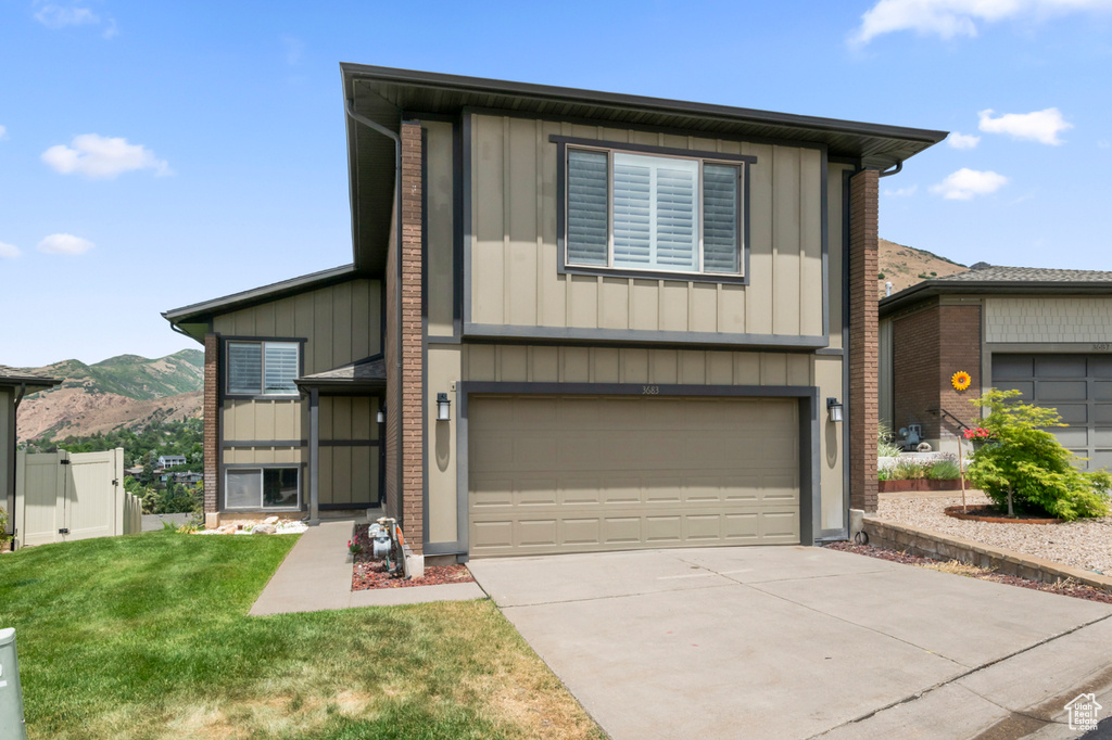 View of front facade featuring board and batten siding, a mountain view, driveway, and an attached garage