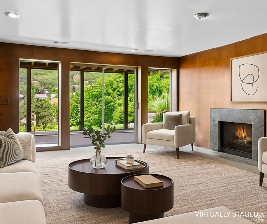 Carpeted living area featuring healthy amount of natural light, a fireplace, and wooden walls