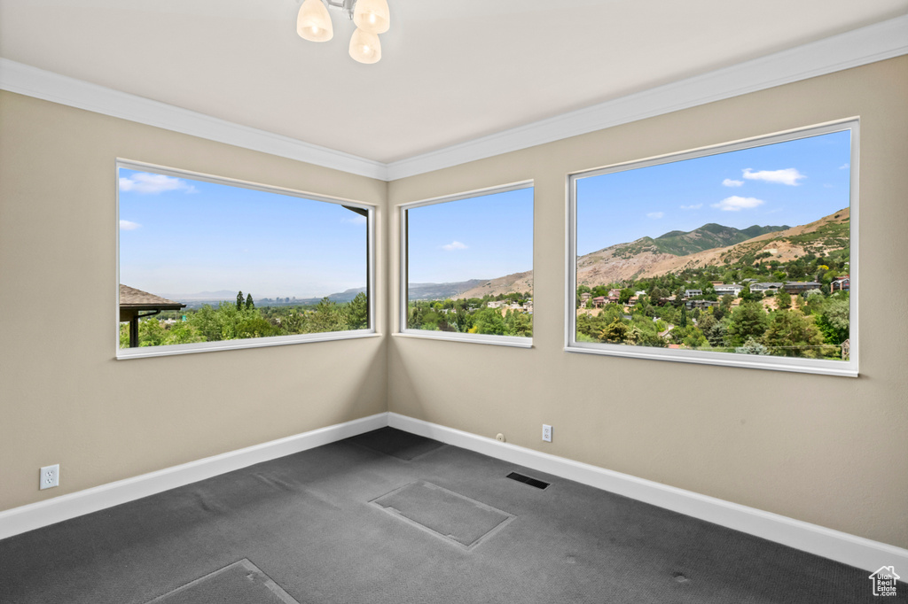 Unfurnished room with a mountain view, a chandelier, dark carpet, and crown molding