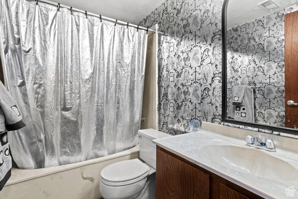 Full bath with wallpapered walls, vanity, and shower / tub combo