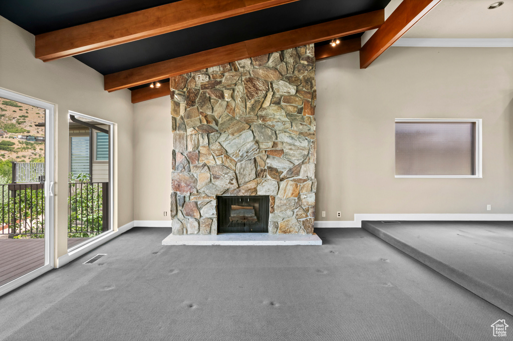 Unfurnished living room featuring beamed ceiling, a fireplace, and carpet floors