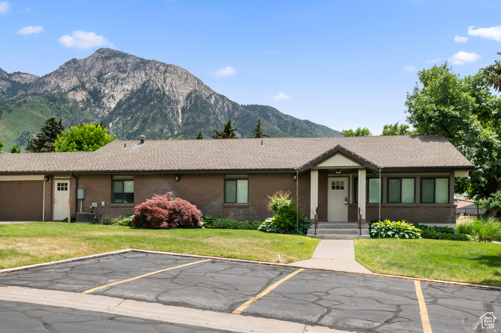 View of front of property featuring a mountain view, brick siding, uncovered parking, and a front yard