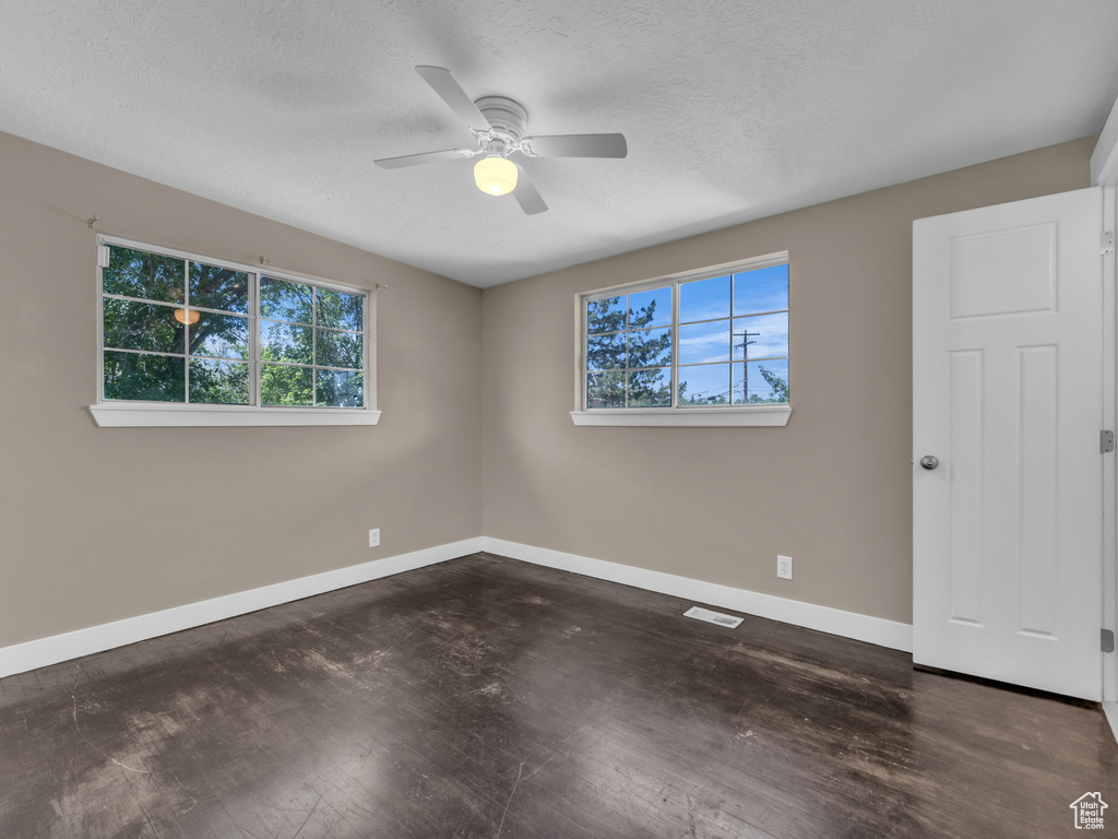 Spare room with healthy amount of natural light, wood finished floors, and a textured ceiling