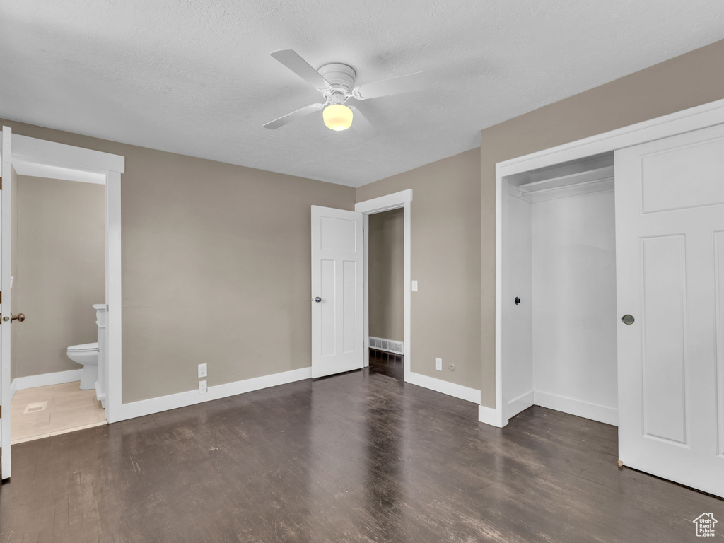 Unfurnished bedroom with wood finished floors, a closet, a ceiling fan, and ensuite bathroom