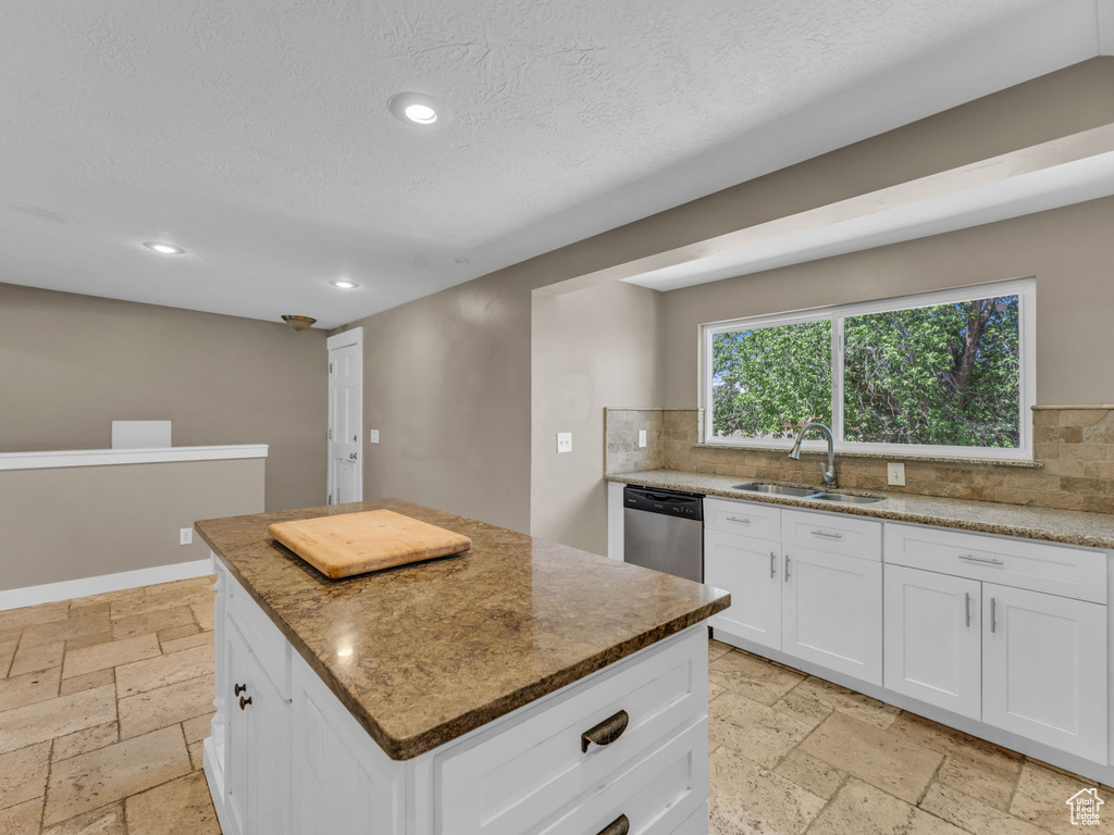 Kitchen featuring stone tile floors, dishwasher, recessed lighting, tasteful backsplash, and a textured ceiling