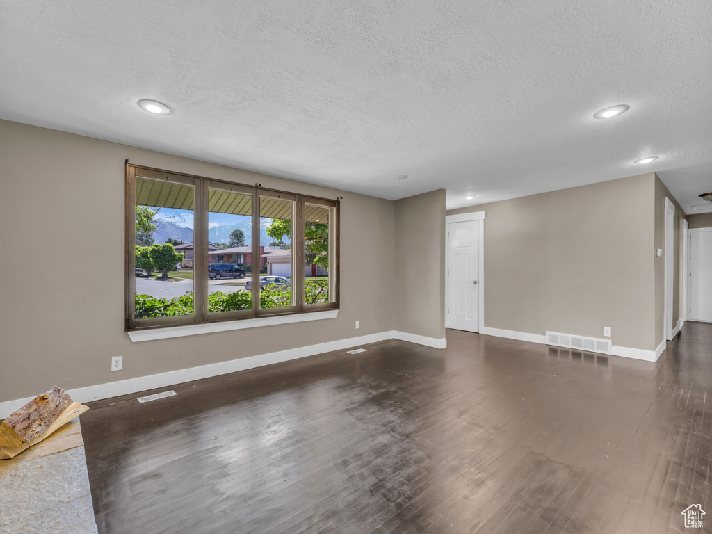 Unfurnished living room with recessed lighting, dark wood-style flooring, and a textured ceiling