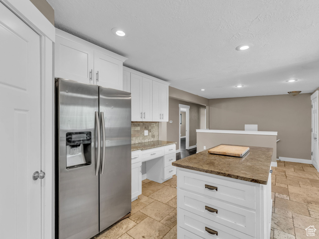 Kitchen with stainless steel fridge with ice dispenser, stone tile floors, recessed lighting, decorative backsplash, and white cabinets