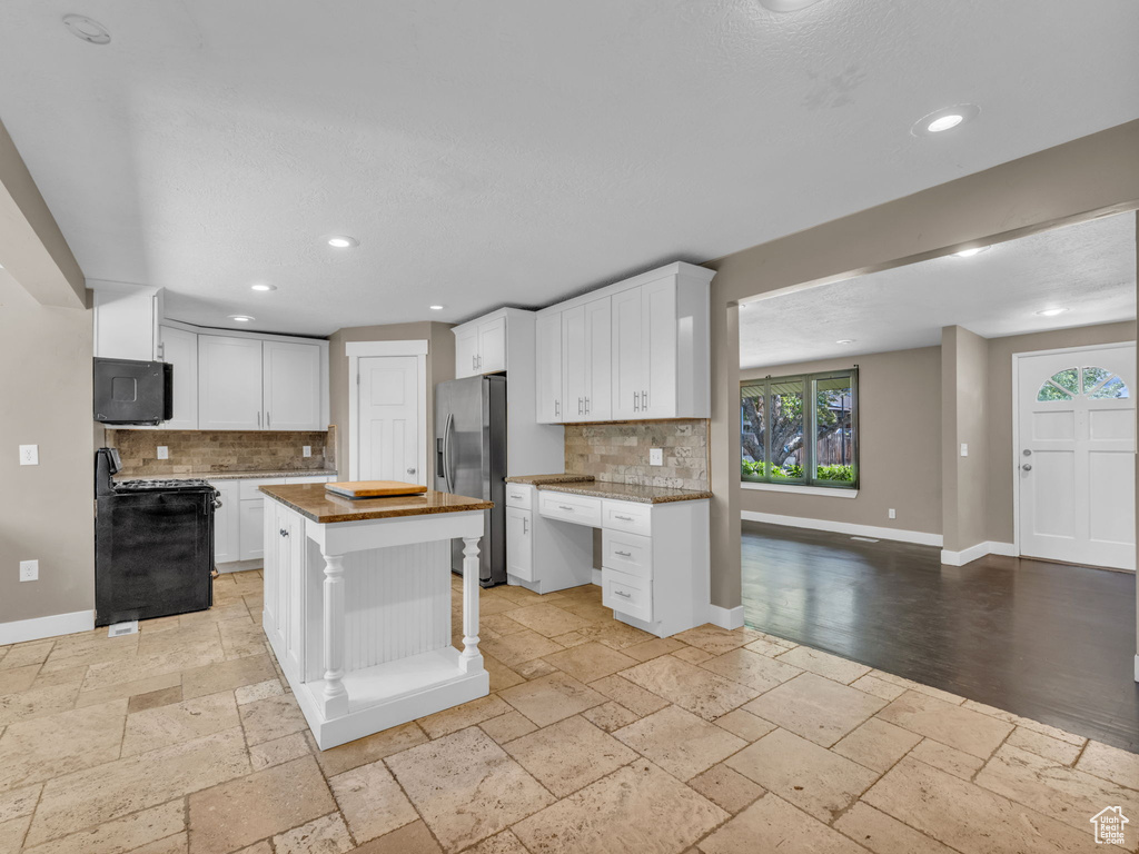 Kitchen with stainless steel fridge with ice dispenser, gas range, stone tile floors, backsplash, and recessed lighting