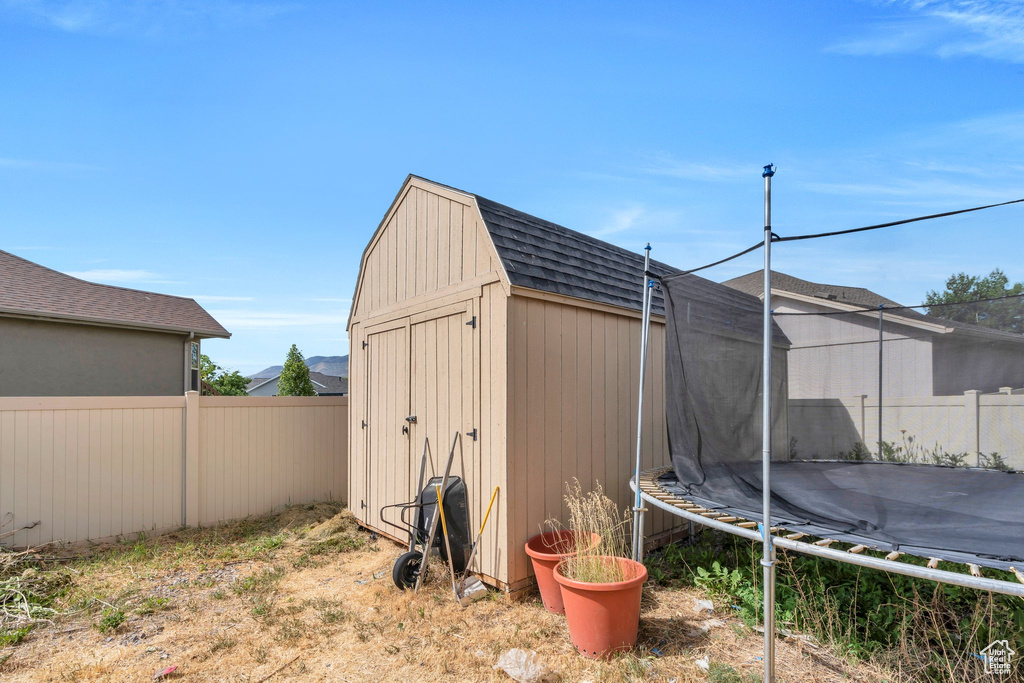 View of shed with a trampoline and a fenced backyard