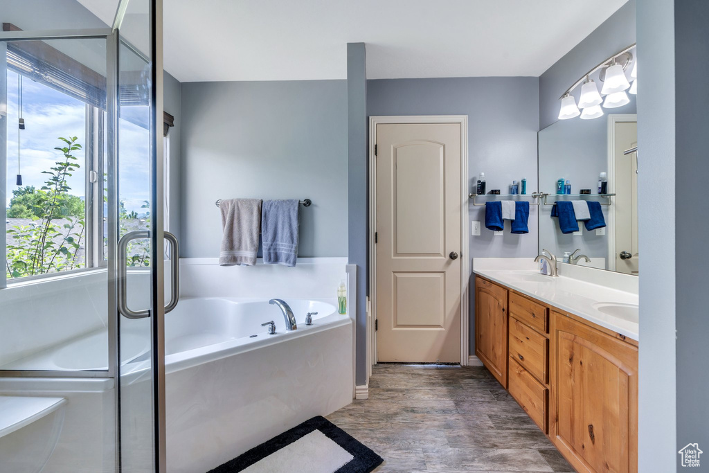 Bathroom with plenty of natural light, double vanity, a bath, and wood finished floors